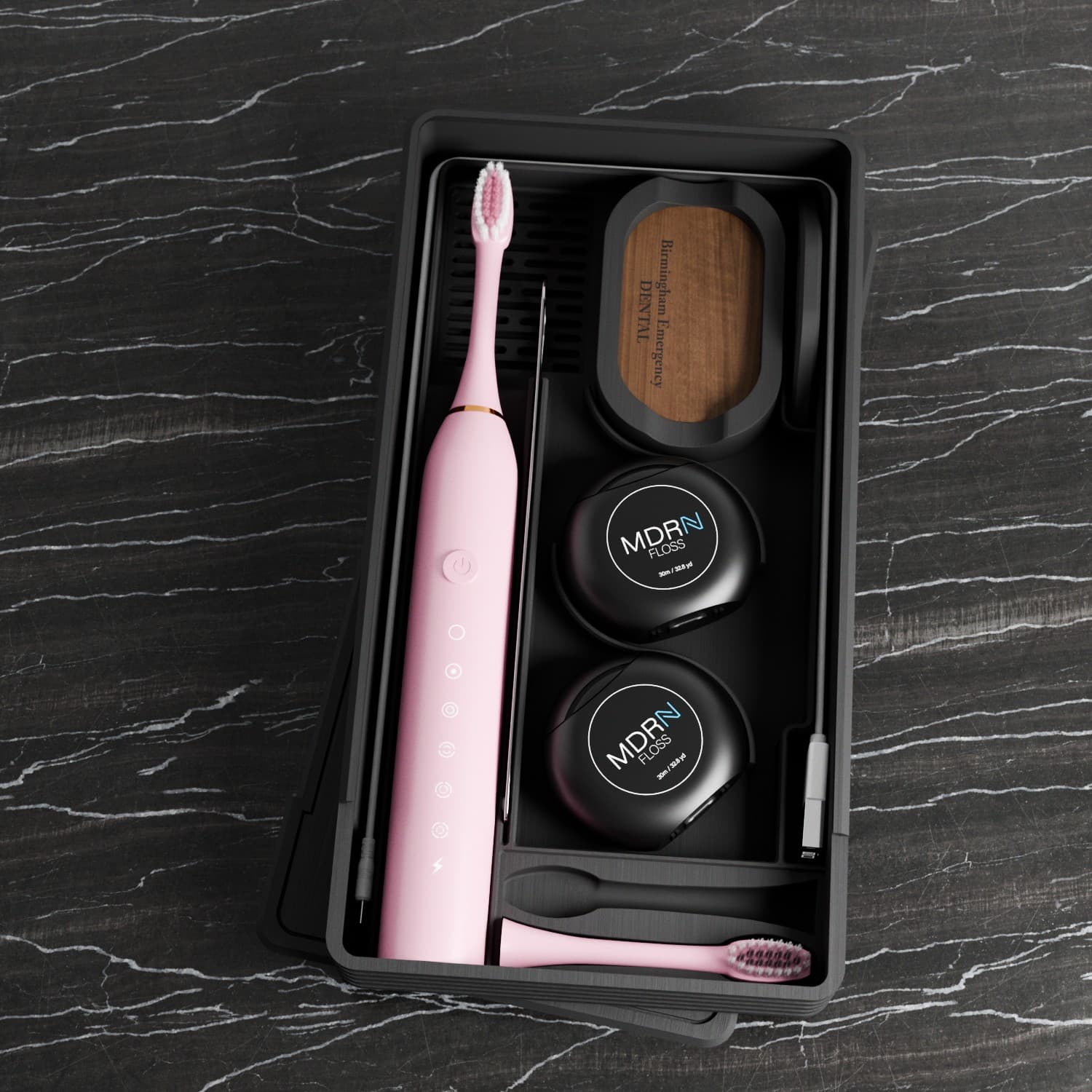 Pink-brush dental kit arranged on black marble
