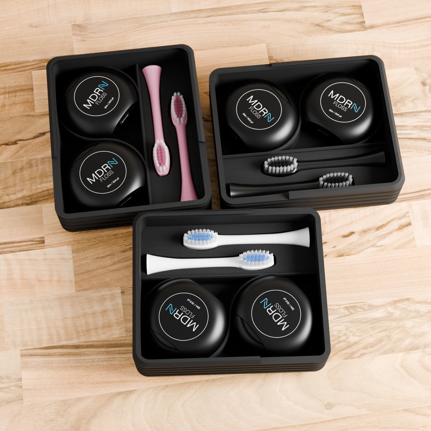 Three compact dental kit trays arranged on wood surface