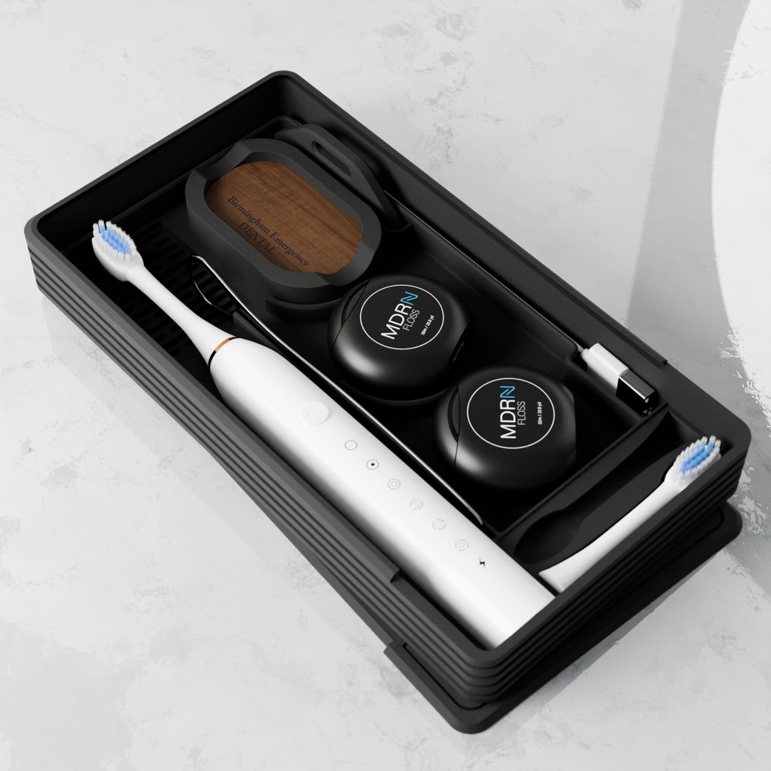 Black tray with white electric toothbrush and floss