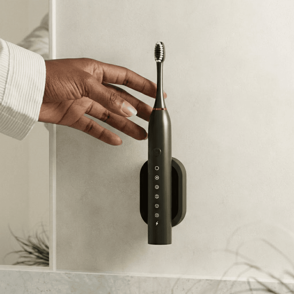 Hand reaching for wall-mounted black electric toothbrush